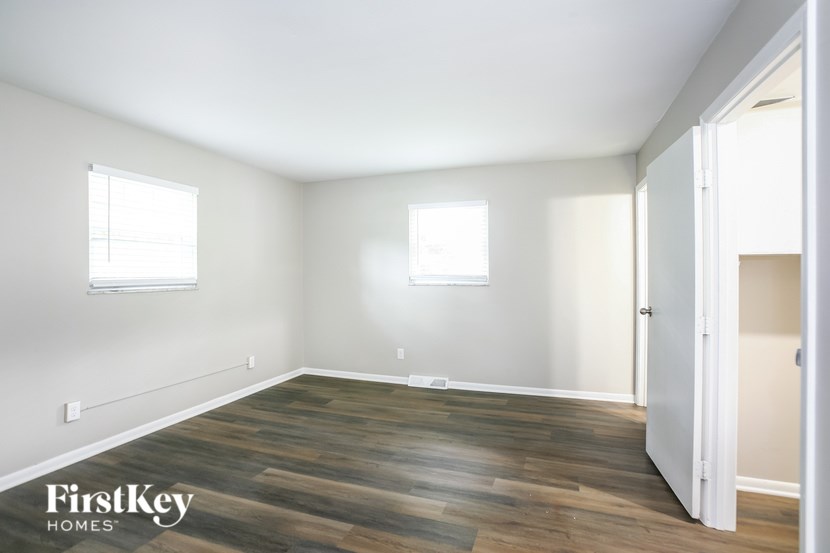 A room with wooden flooring and two windows.