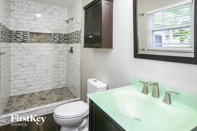 A bathroom with a white toilet, a green sink, and a mirror.