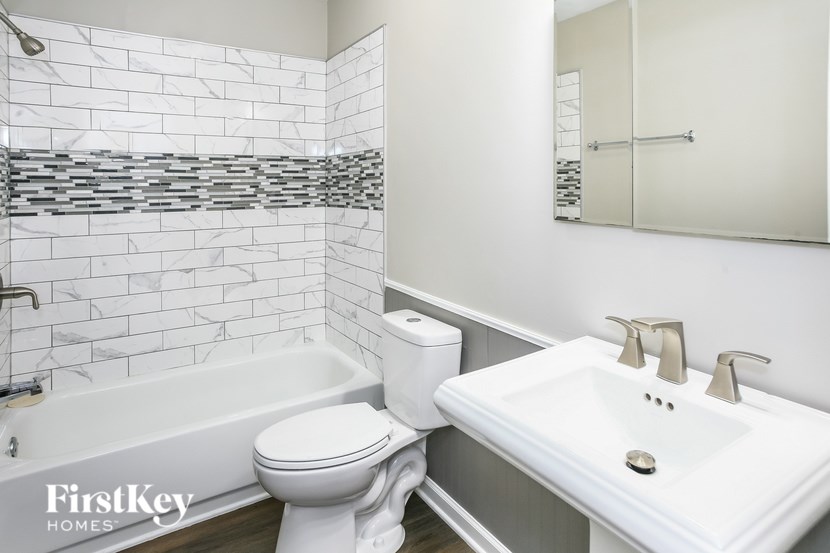 A white bathroom with a white toilet, sink, and a white bathtub.