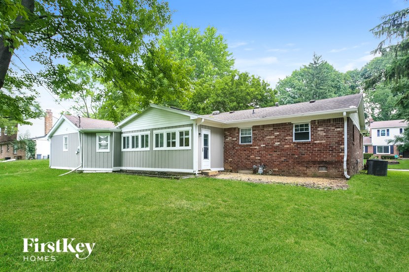 A house with a green lawn and trees in the background.