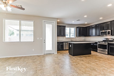 A kitchen with black cabinets and a wooden floor.