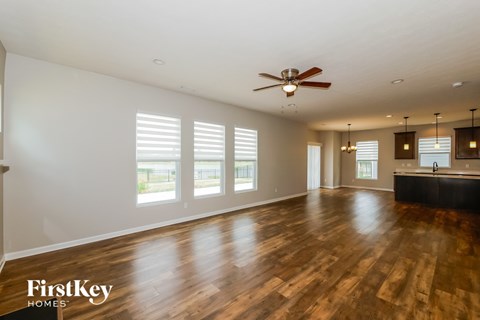 A spacious room with wooden floors and a ceiling fan.