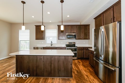 A modern kitchen with wooden cabinets and a stainless steel refrigerator.