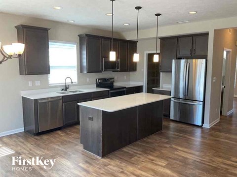 A modern kitchen with dark wood cabinets and stainless steel appliances.