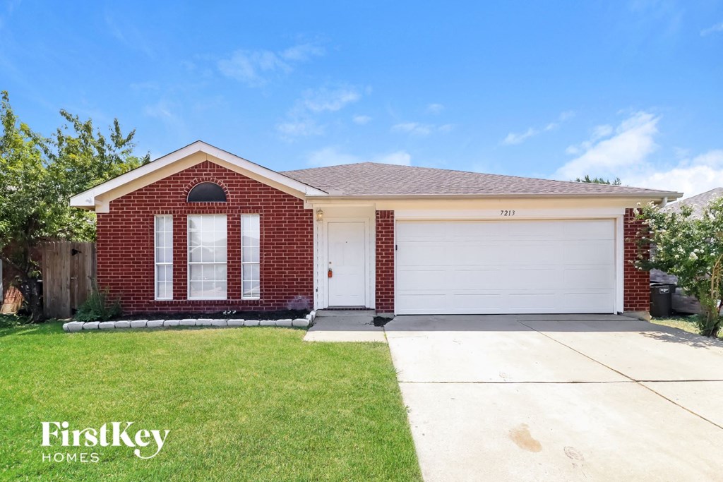 a brick house with a white garage door and a lawn