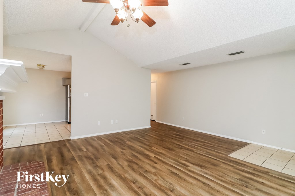 the living room and dining room with wood flooring and a ceiling fan