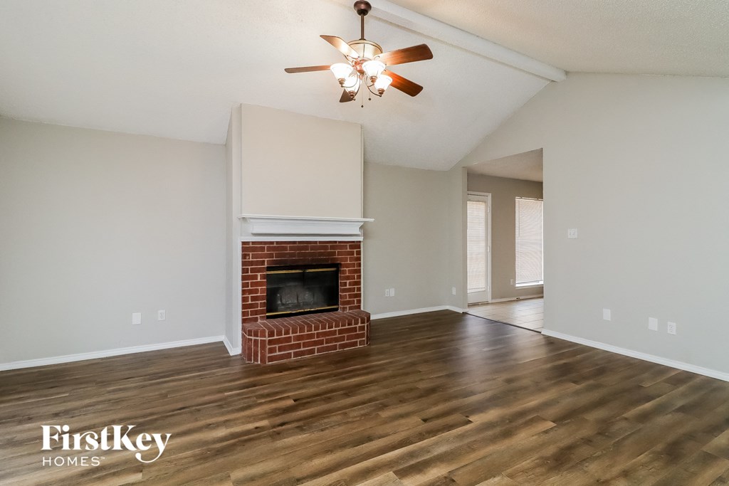 a living room with a brick fireplace and a ceiling fan
