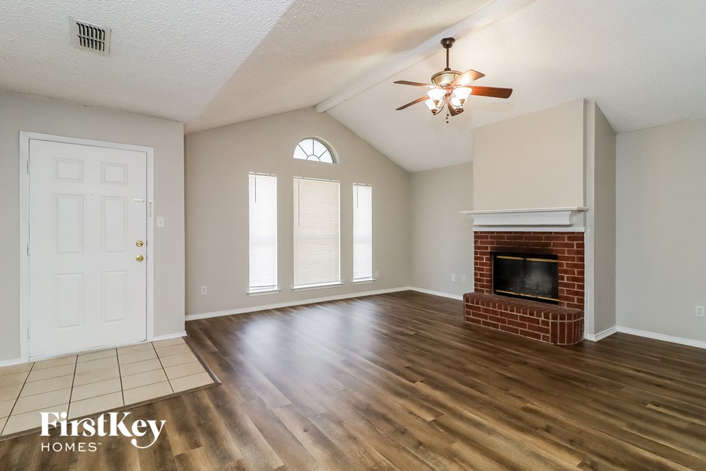 an empty living room with a fireplace and a ceiling fan