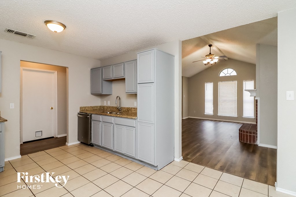an empty kitchen and living room with a hard wood floor and white cabinets