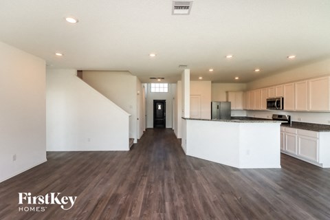 an open kitchen and living room with white cabinets and wood flooring