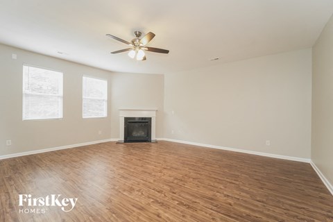 A spacious room with a fireplace and a ceiling fan.
