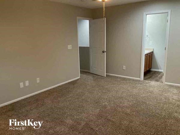 a bedroom with a carpeted floor and a door to a bathroom