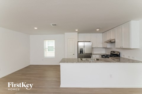 an empty kitchen with white cabinets and a counter top
