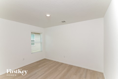 the living room of a home with white walls and wood floors