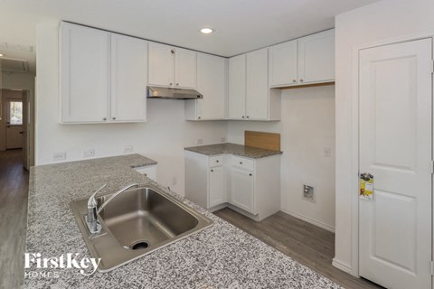 an empty kitchen with white cabinets and a sink