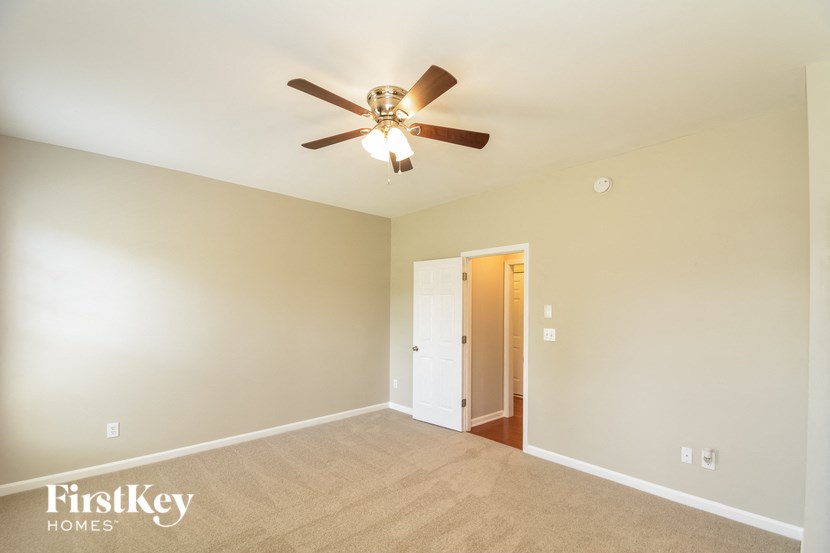 an empty living room with a ceiling fan and a door to a closet