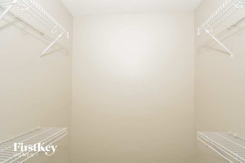 a walk in closet with empty shelves on the wall