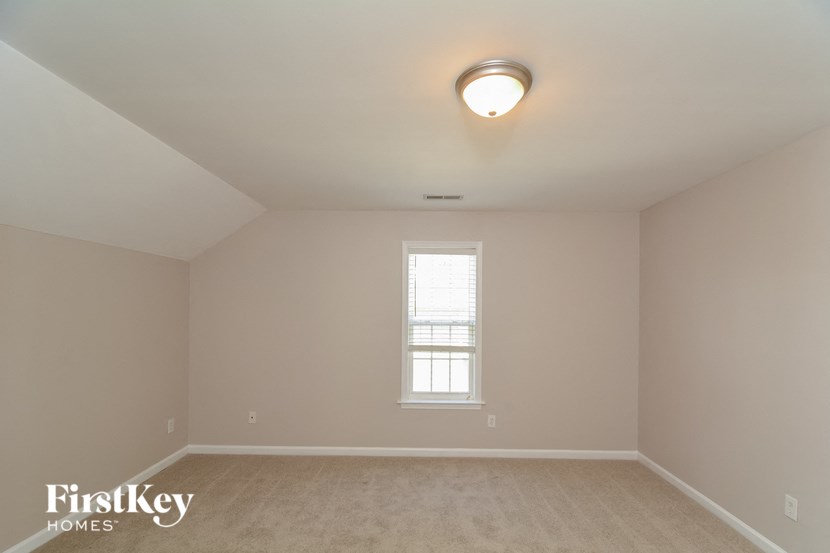 the bedroom of an attic with a window and beige walls