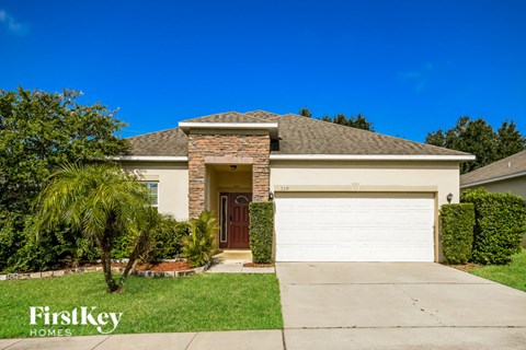 a home with a white garage door and a palm tree