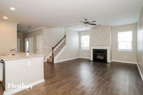 A spacious living room with a fireplace and a staircase.
