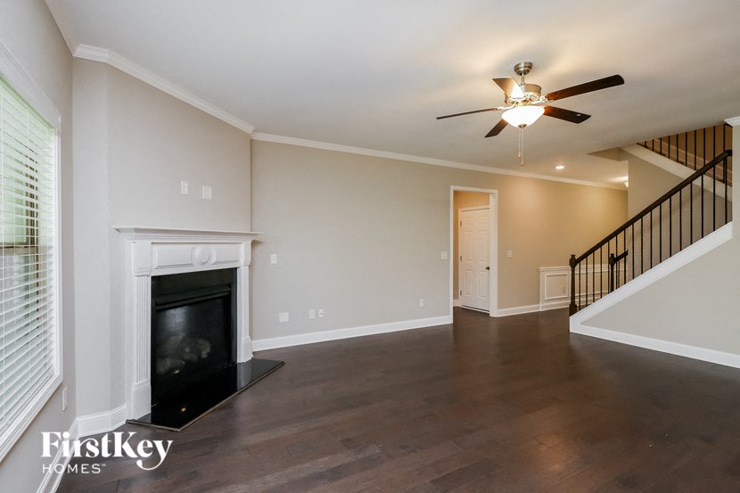 an empty living room with a fireplace and a ceiling fan