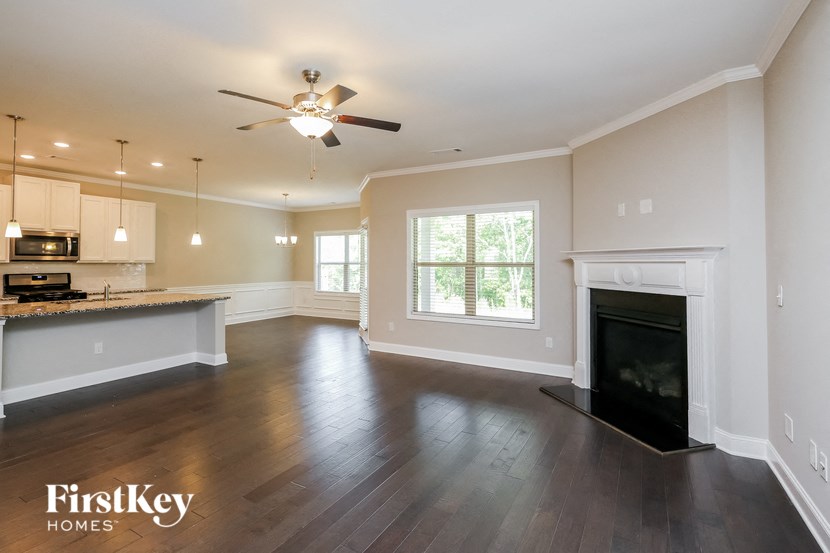an empty living room with a fireplace and a kitchen