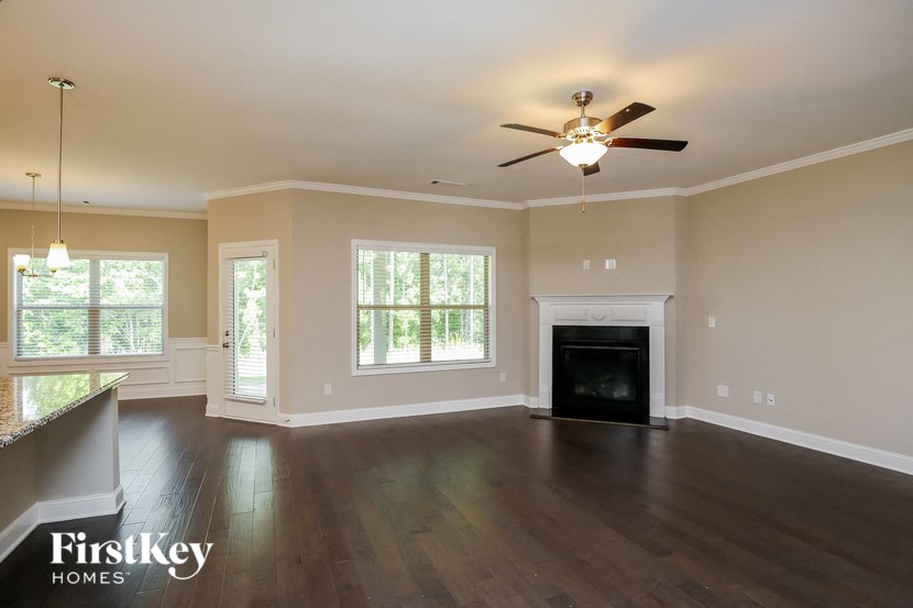 an empty living room with a ceiling fan and a fireplace