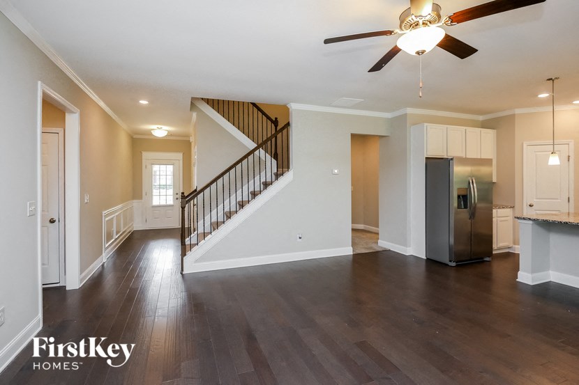 an empty living room with a ceiling fan and a staircase