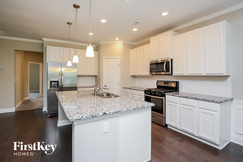 a kitchen with white cabinets and a marble counter top