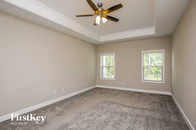 the spacious living room with ceiling fan and carpet