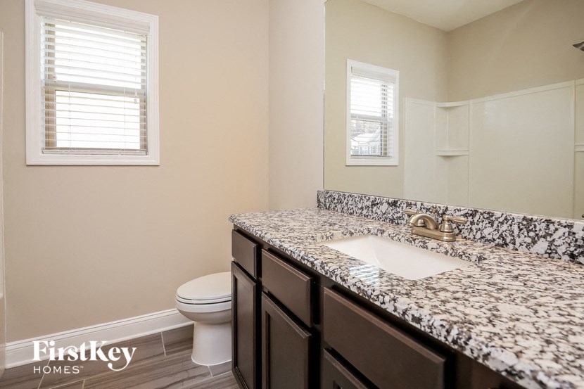 a bathroom with marble counter top and a toilet and sink