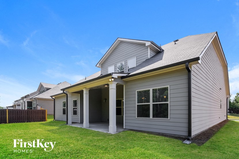 a gray house with white columns and a lawn
