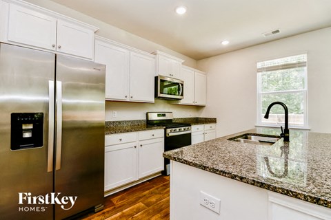 A kitchen with a stainless steel refrigerator and granite countertops.