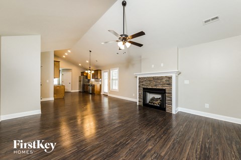A spacious living room with a fireplace and a ceiling fan.