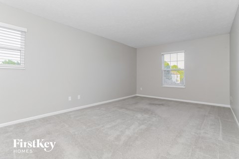 an empty bedroom with two windows and a cement floor