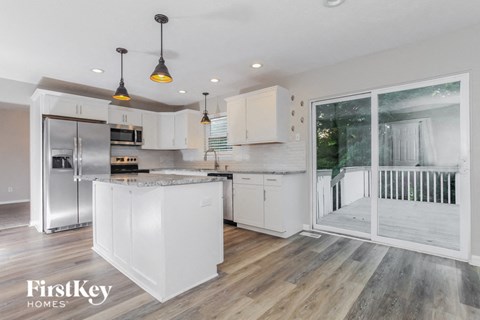 a kitchen with white cabinets and a sliding glass door