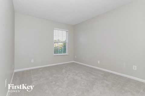 an empty living room with a window and carpet