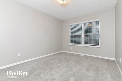 a bedroom with a window and a carpeted floor
