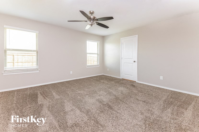 an empty living room with carpet and a ceiling fan