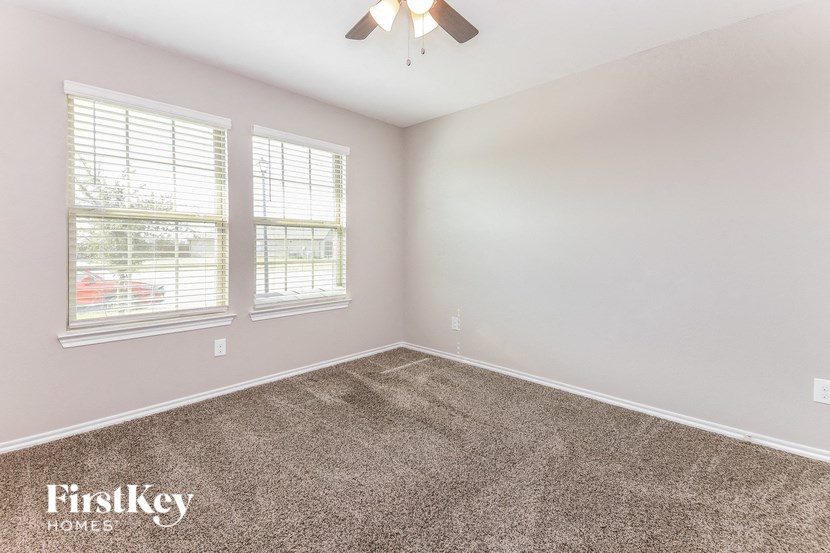 a bedroom with carpet and two windows and a ceiling fan