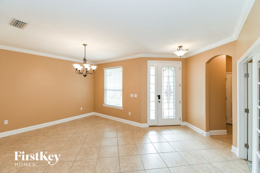 A spacious room with a chandelier and a door leading to another room.
