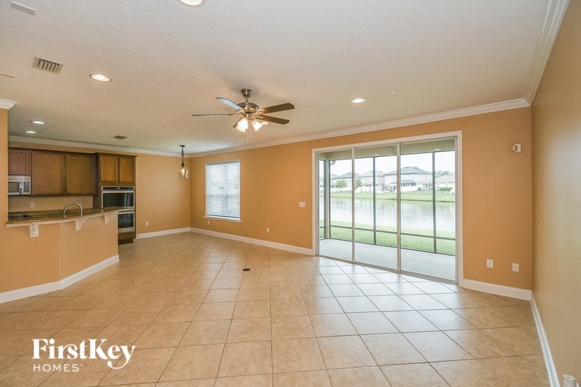 A spacious room with a ceiling fan and sliding glass doors leading to a grassy area.