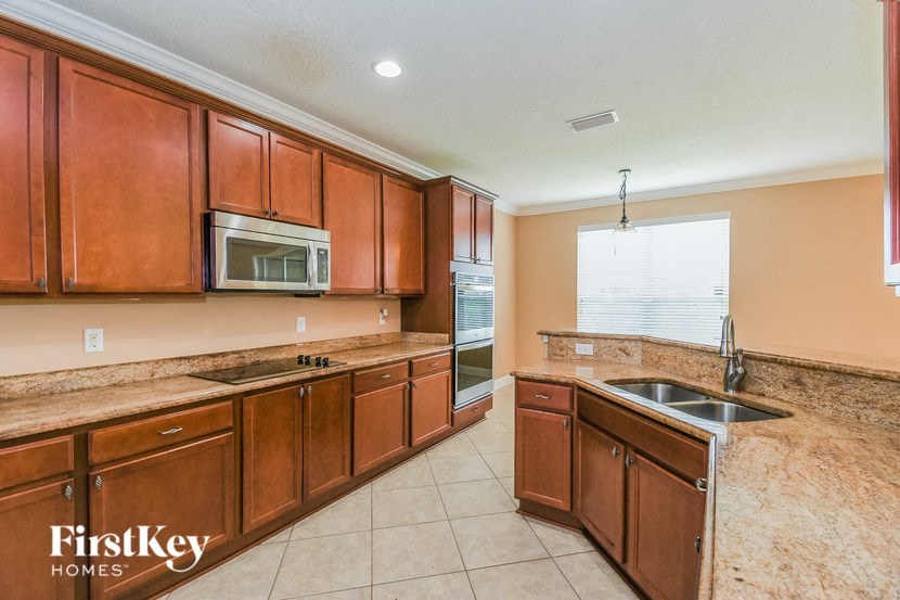 A kitchen with brown cabinets and a microwave.