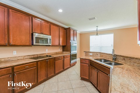 A kitchen with brown cabinets and a microwave.