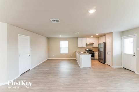 A spacious kitchen with white cabinets and a refrigerator is seen in the image.
