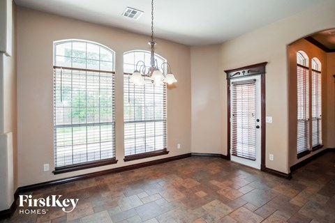 an empty dining room with three large windows and a chandelier