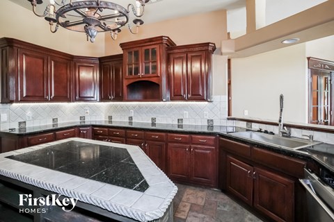 a kitchen with dark wood cabinets and black countertops and a black and white island