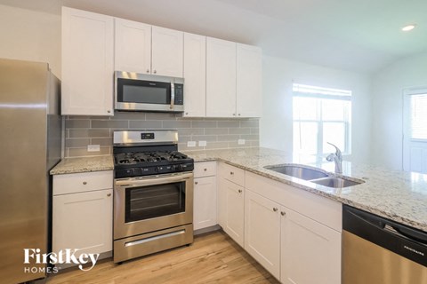A kitchen with white cabinets and a stainless steel refrigerator.