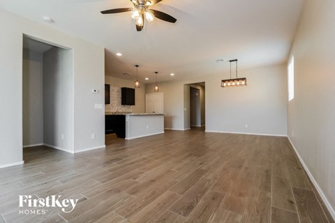 an empty living room and kitchen with a ceiling fan