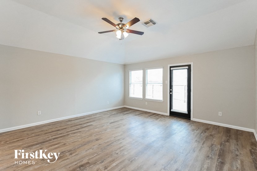 an empty living room with wood floors and a ceiling fan